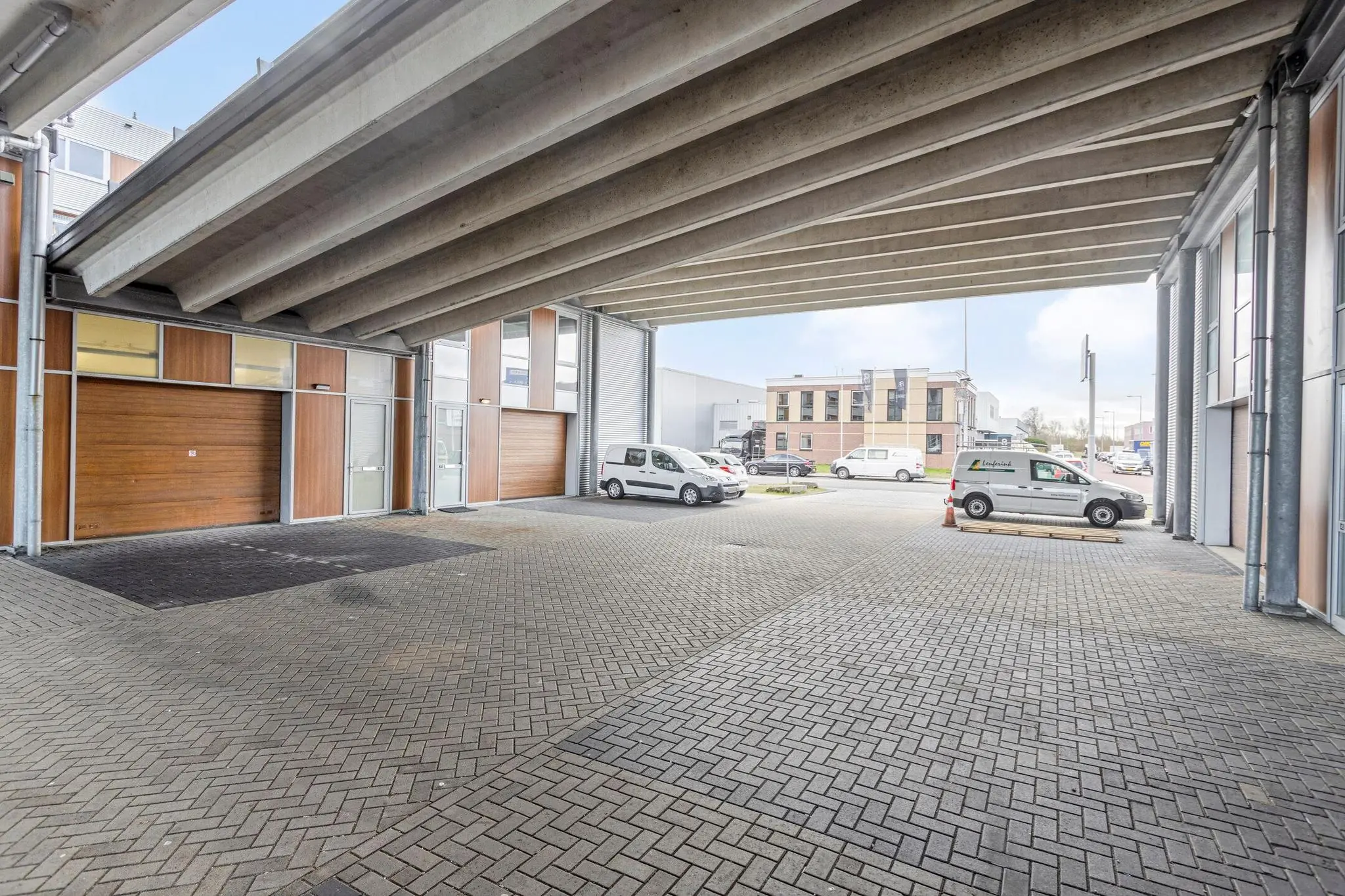 Overdekte parkeer- en bedrijfsruimte aan de Tijnmuiden met zicht op kantoren en geparkeerde bedrijfswagens.
