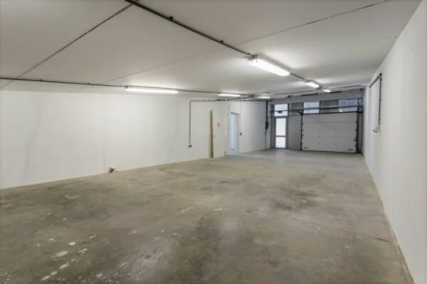 Lege, goed verlichte garage of bedrijfsruimte met betonnen vloer en witte muren aan de Tijnmuiden.