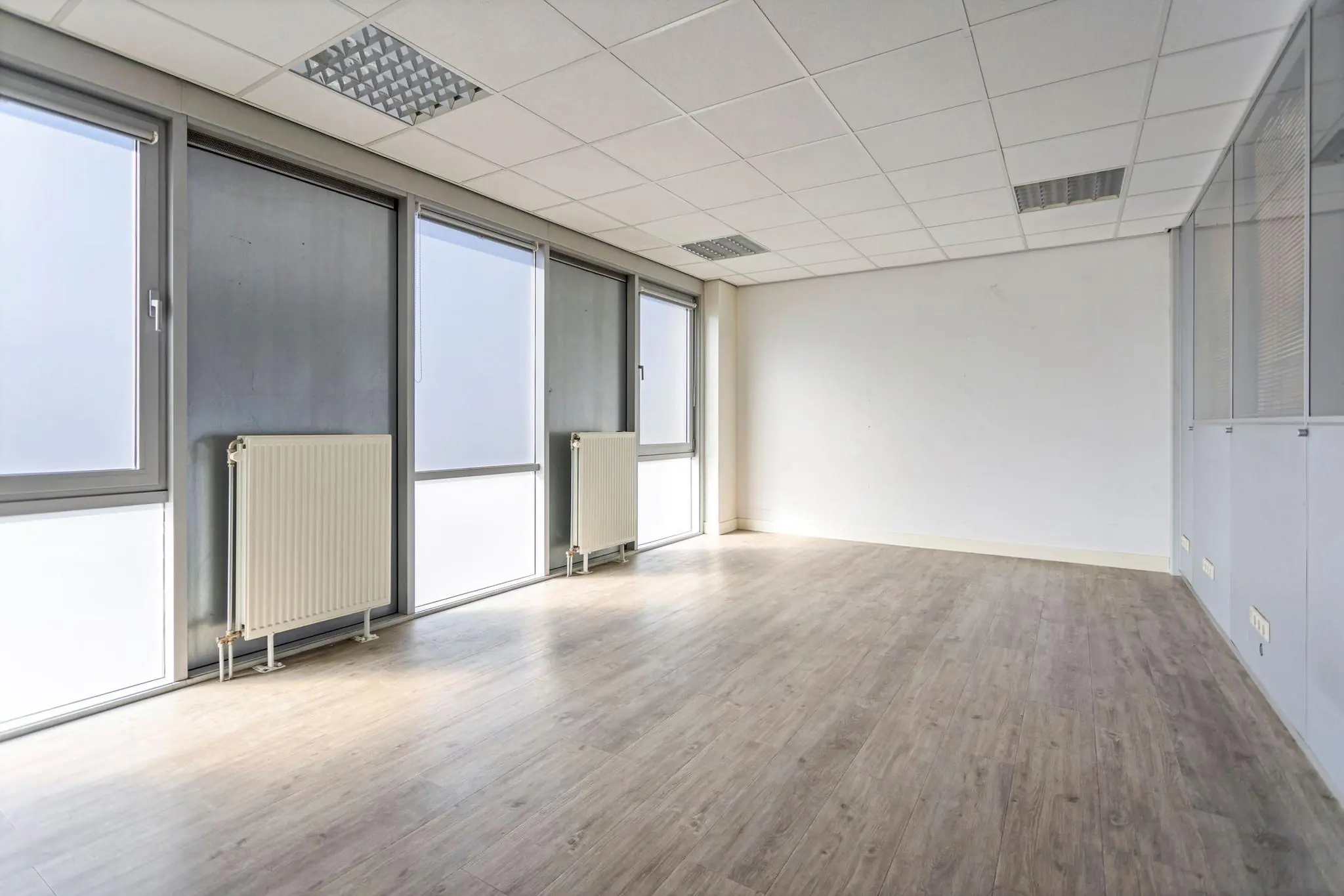 Lichte, lege kantoorruimte aan de Tijnmuiden met grote ramen en een houten vloer.