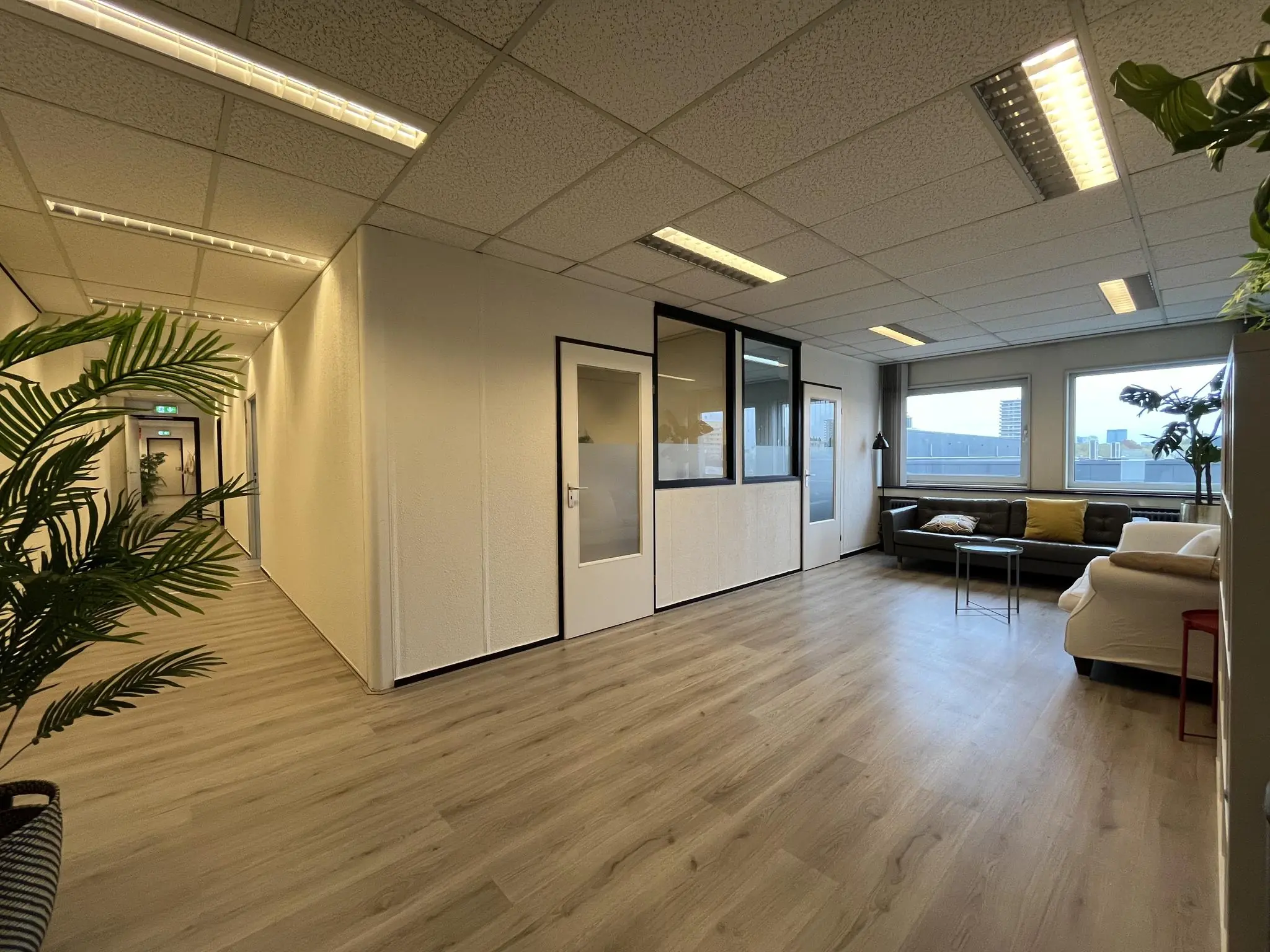 Moderne kantoorruimte aan de Hollantlaan met wachtruimte, glazen kantoorwanden en grote ramen met uitzicht op de stad.