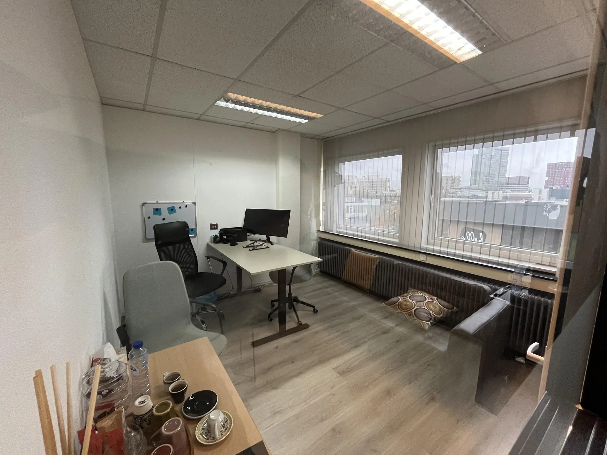 Modern kantoor aan de Hollantlaan met bureau, zitplekken, koffietafel en uitzicht op de stad.