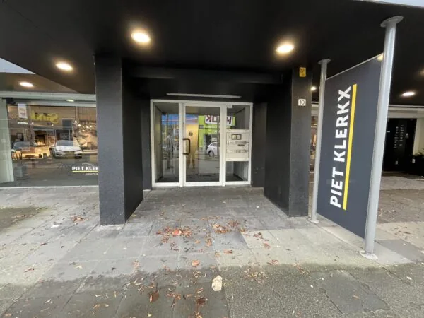 Ingang van het gebouw aan de Hollantlaan 10 met een bord van meubelwinkel Piet Klerkx.