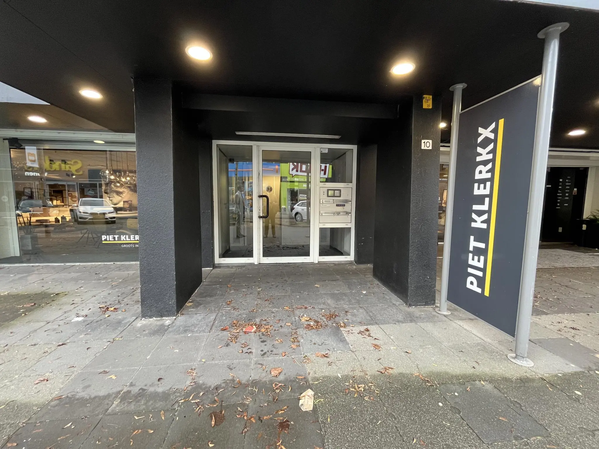 Ingang van het gebouw aan de Hollantlaan 10 met een bord van meubelwinkel Piet Klerkx.
