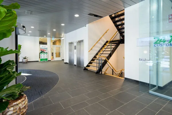 Moderne en nette entreehal in een kantoorgebouw in Trondheim met een trap, liften en planten.