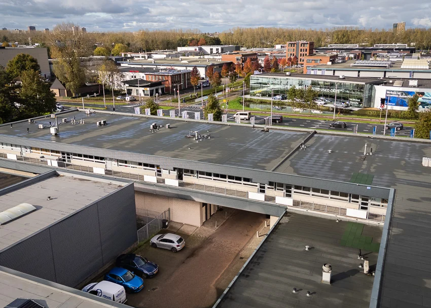 Luchtfoto van industrieterrein aan de Hoofdweg met kantoorgebouwen, parkeerplaatsen en autodealer.
