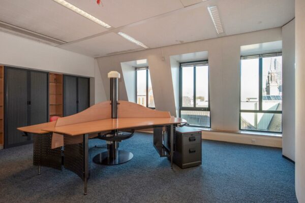 Kantoorruimte aan de Doelenstraat met hoekbureau, archiefkasten en uitzicht op de stad.