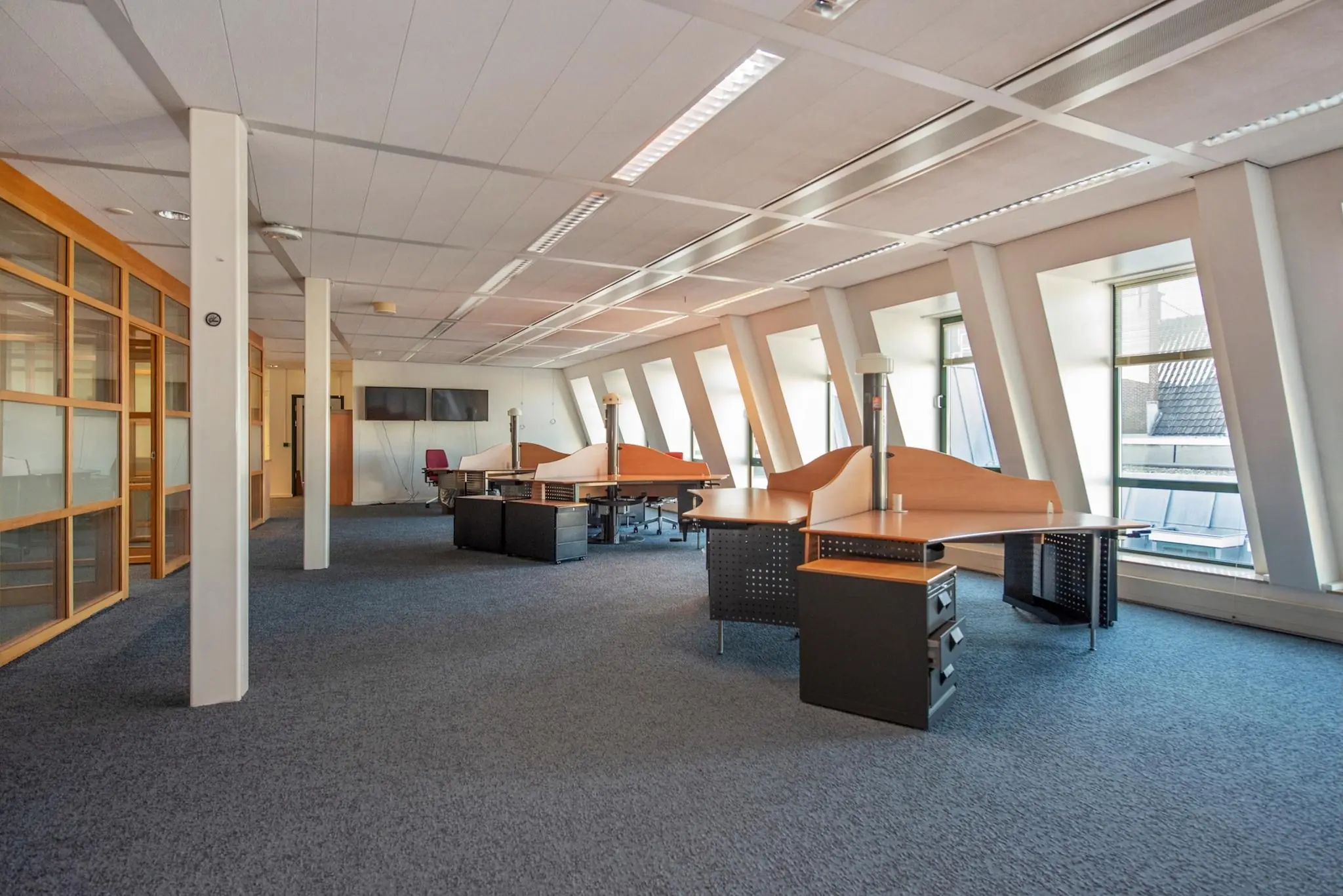 Ruime en lichte kantoorruimte aan de Doelenstraat met meerdere werkplekken en grote ramen.