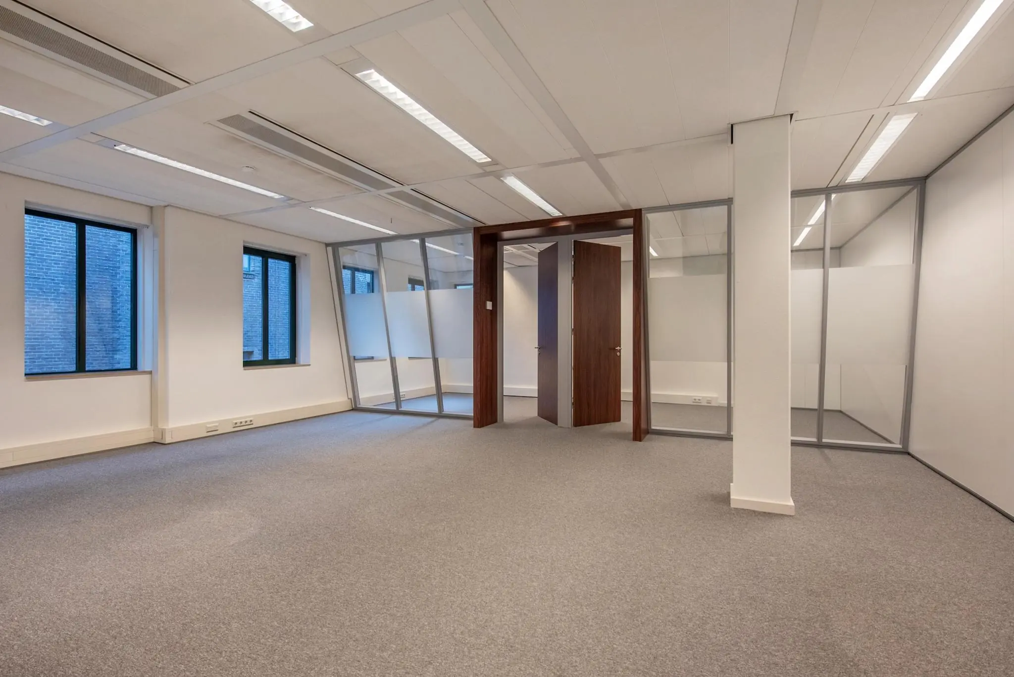 Licht en modern kantoorpand aan de Doelenstraat met glazen wanden en tapijtvloer.