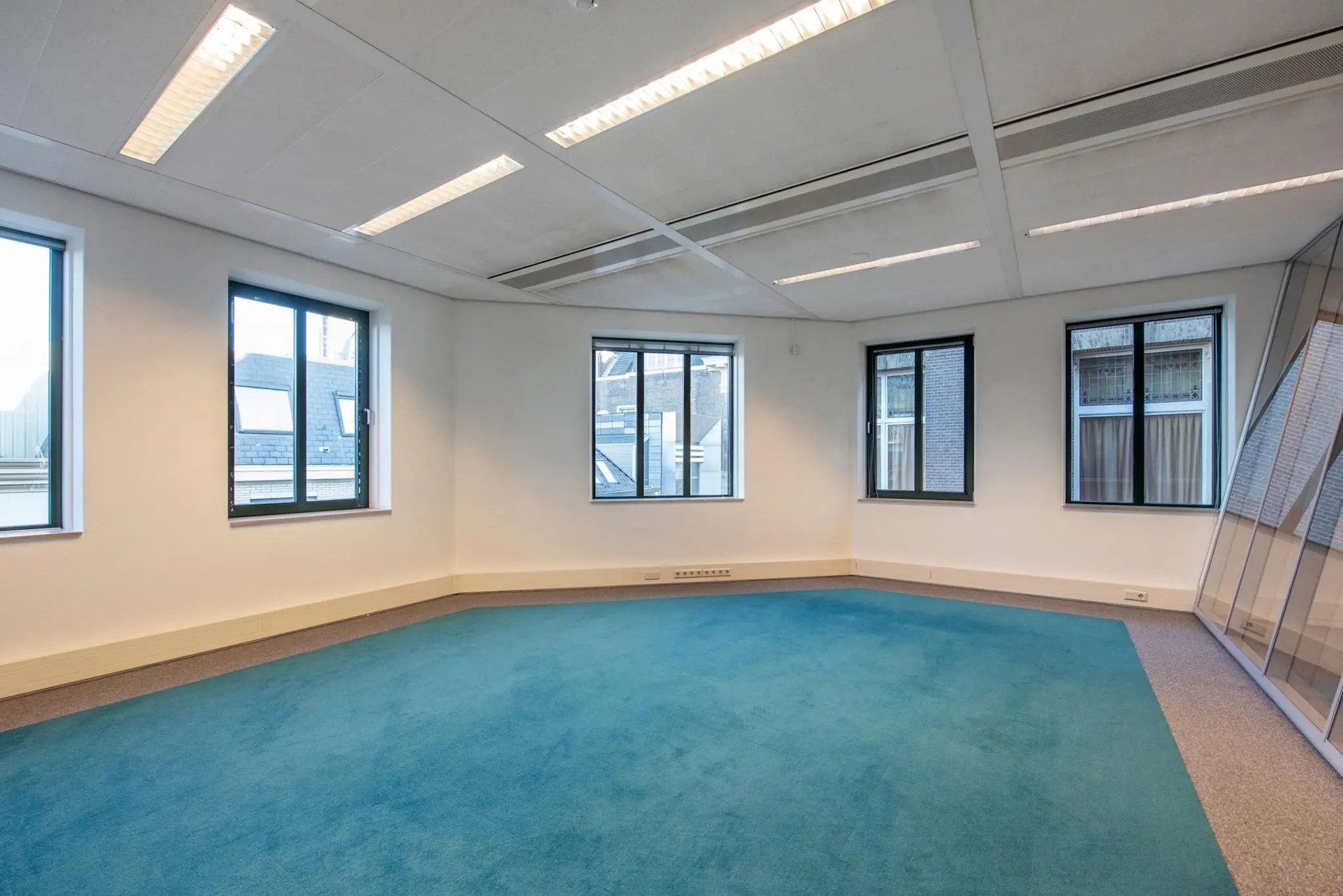 Licht en leeg kantoor met een blauwe vloerbedekking aan de Doelenstraat.