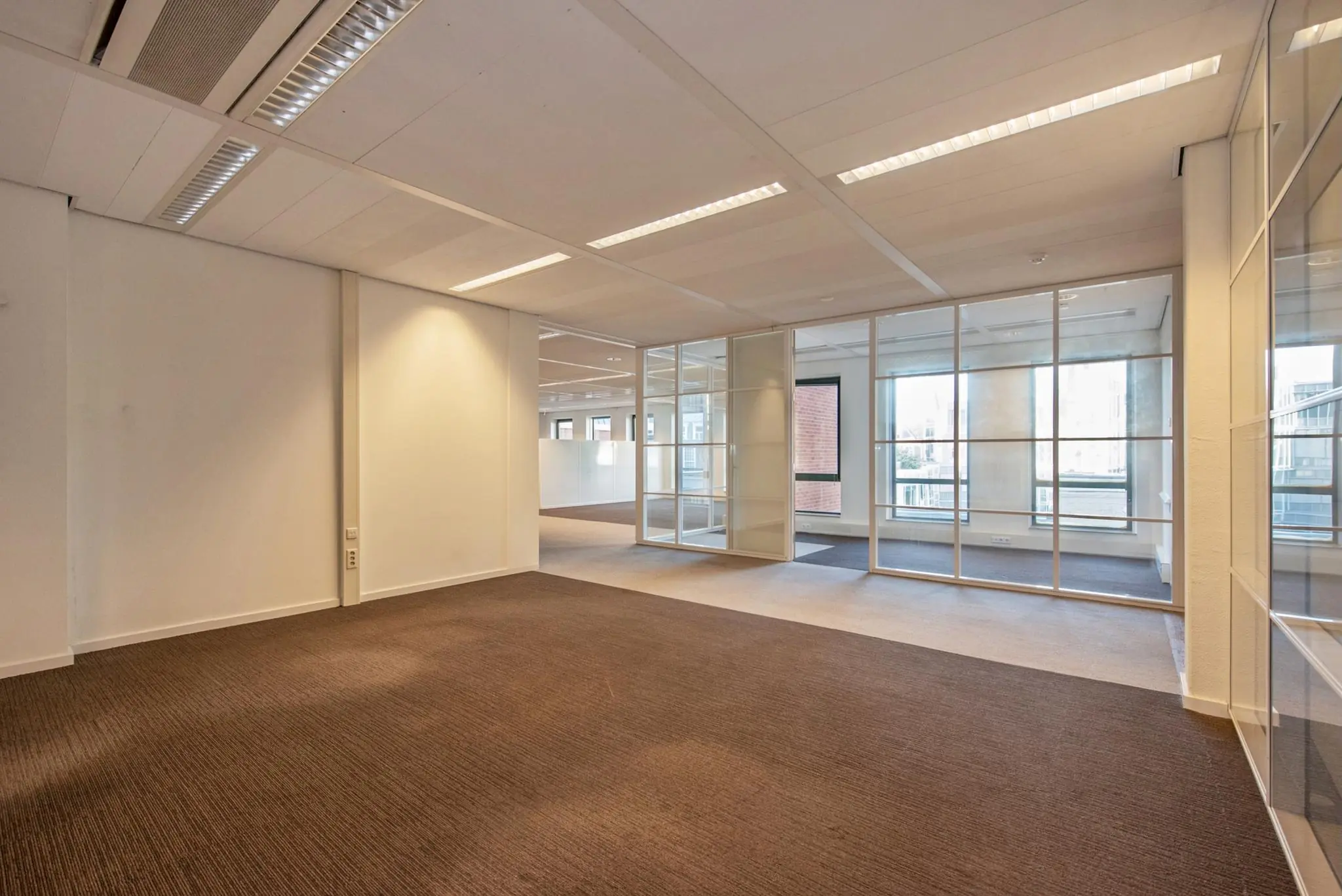 Licht en modern kantoorpand aan de Doelenstraat met glazen scheidingswanden en tapijtvloer.