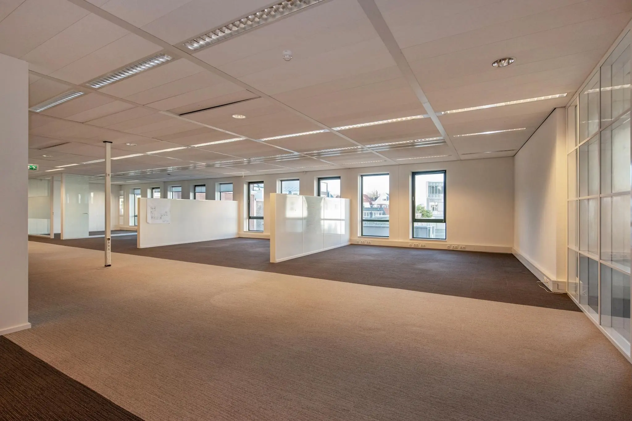 Lichte, moderne kantoorruimte aan de Doelenstraat met glazen wanden, systeemplafond en grote ramen.