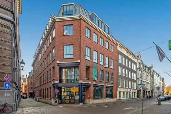 Hoekpand met rode bakstenen en moderne ramen aan de Doelenstraat in een stedelijke omgeving.