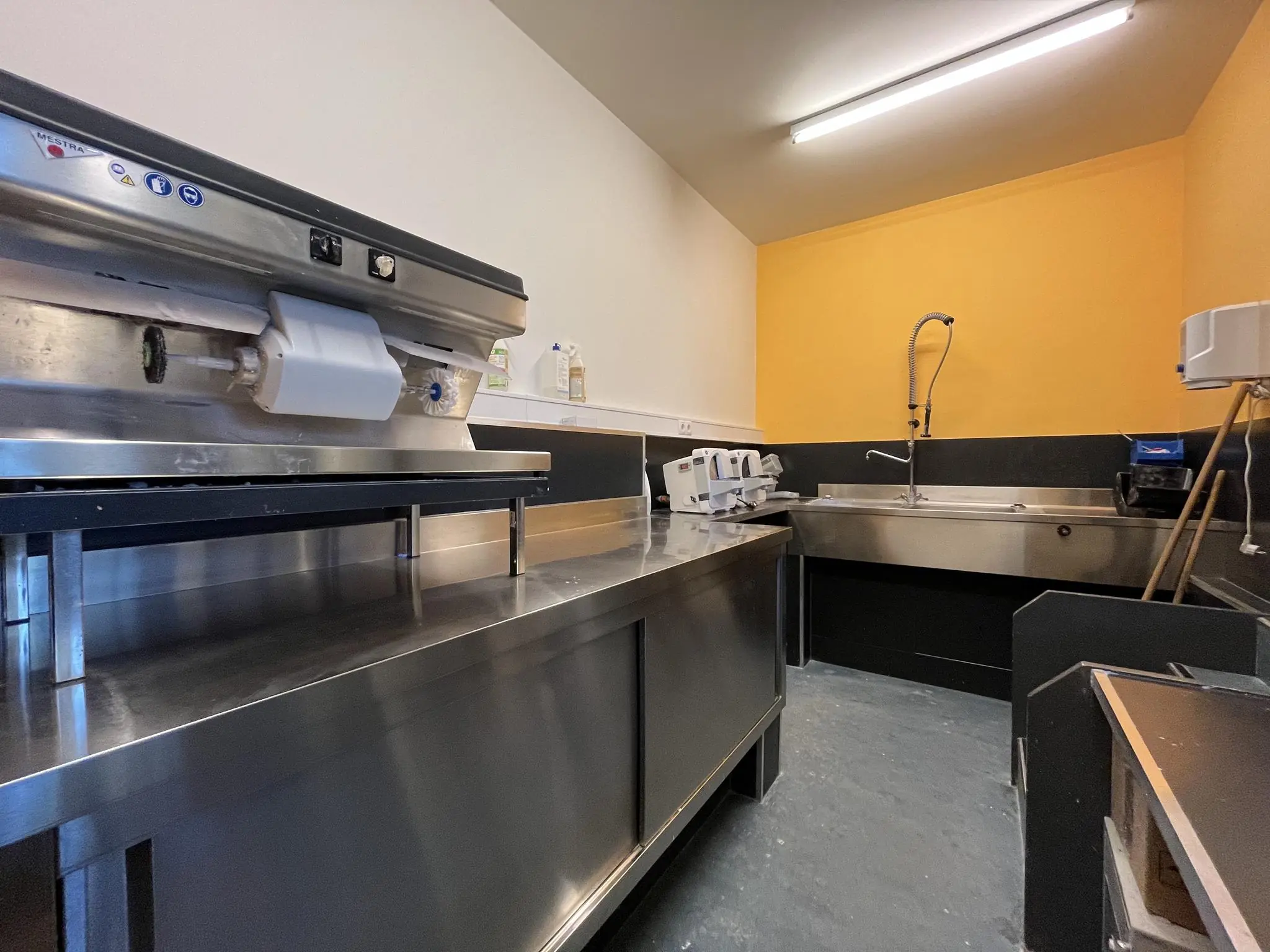 RVS-werkruimte met spoelbak en keukenapparatuur in een functionele ruimte aan de Kerkstraat.