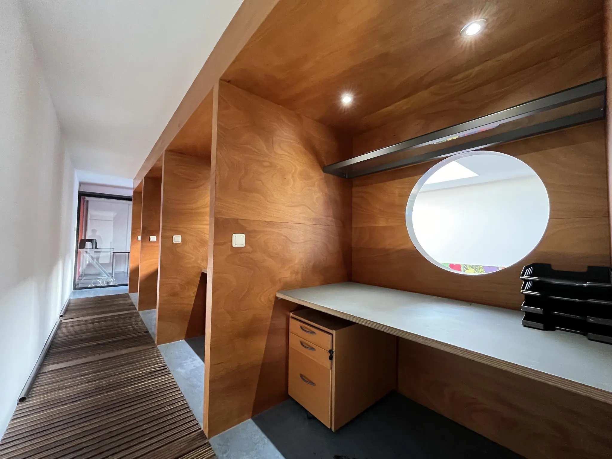 Gang met ingebouwde houten werkplekken en rond raam bij Kerkstraat 173.