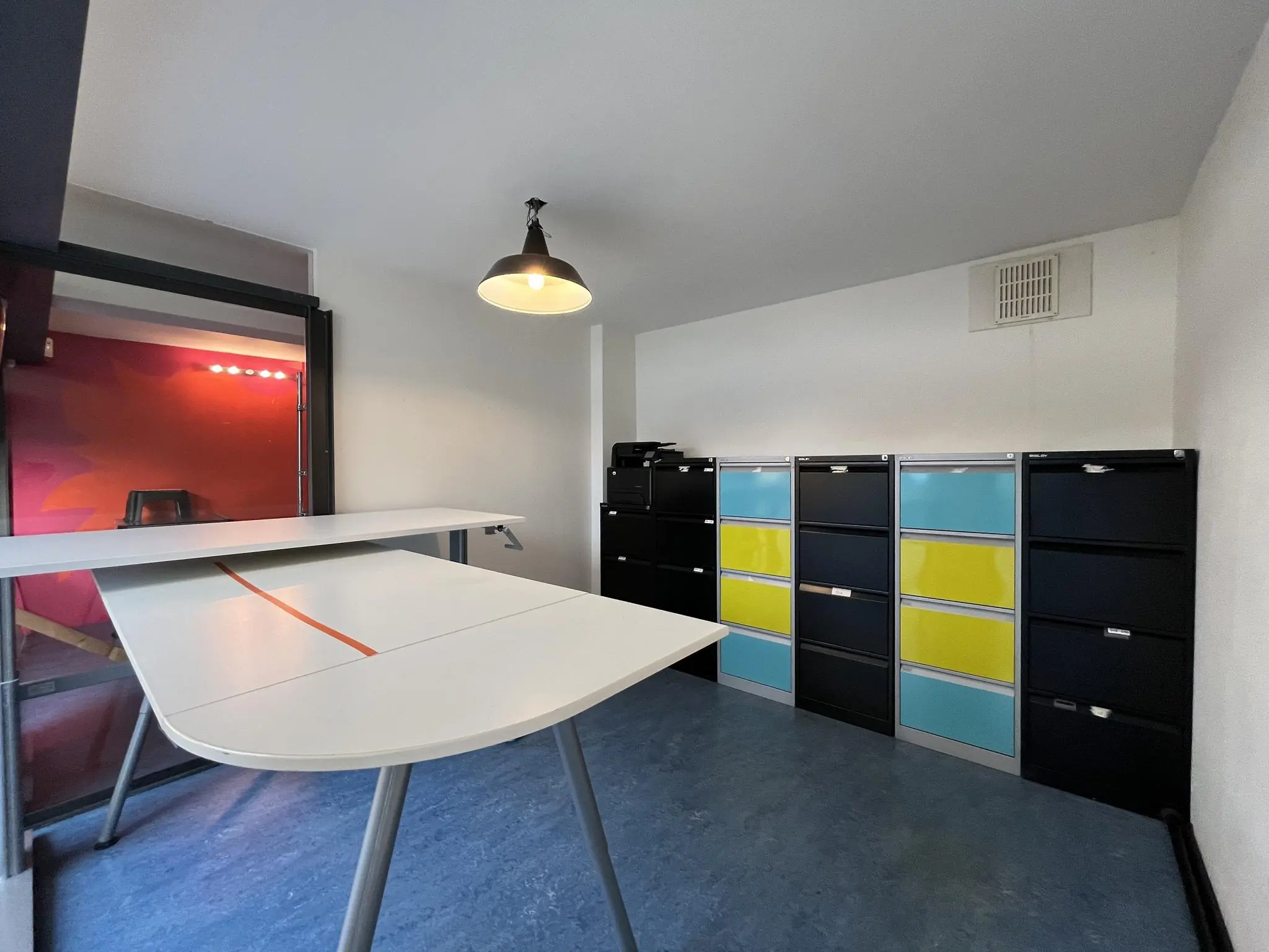 Kantoorruimte aan de Kerkstraat met een wit bureau en een rij kleurrijke archiefkasten tegen de muur.