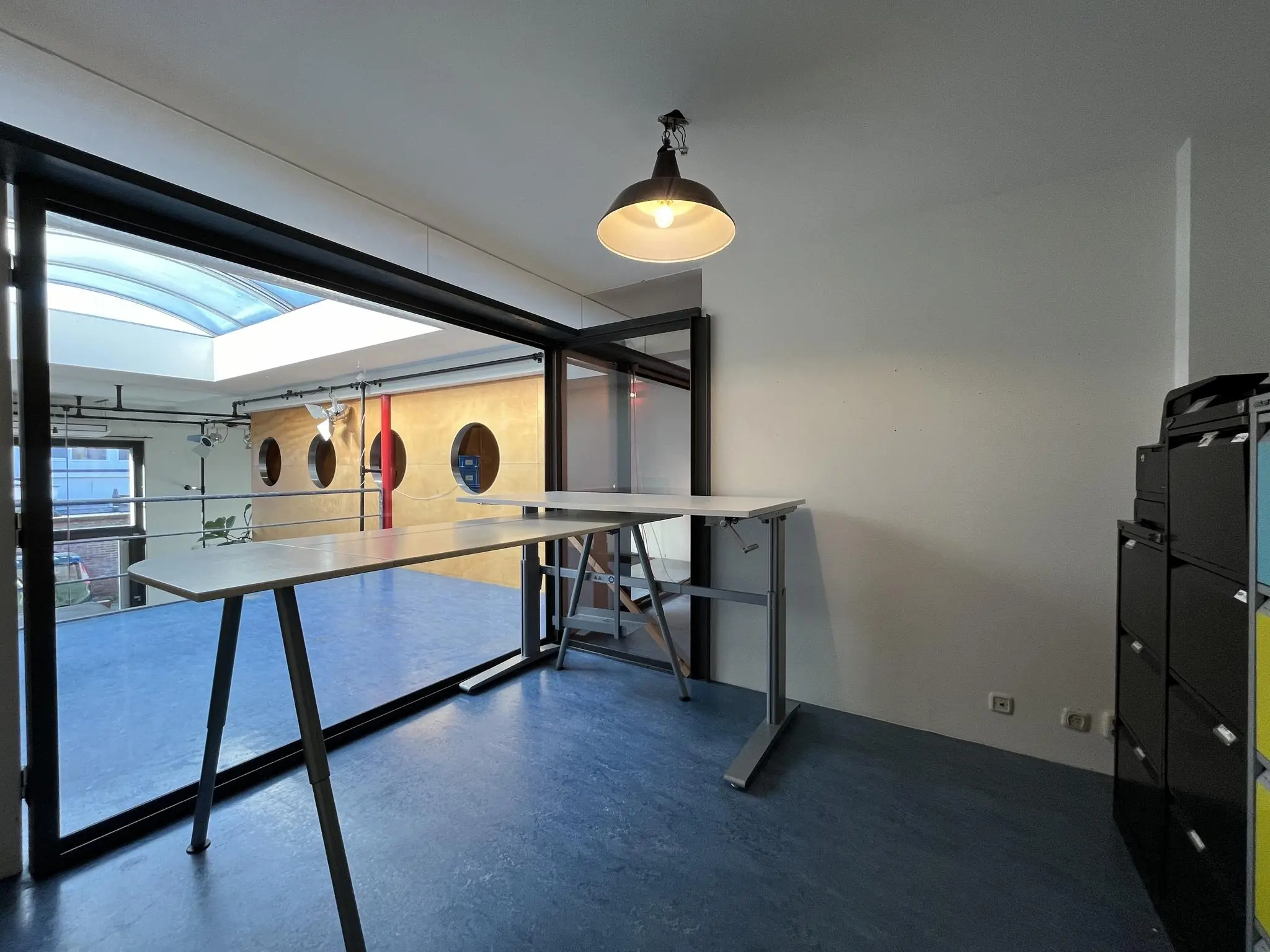 Modern kantoor met een hoog verstelbaar bureau en glazen wand aan de Kerkstraat.