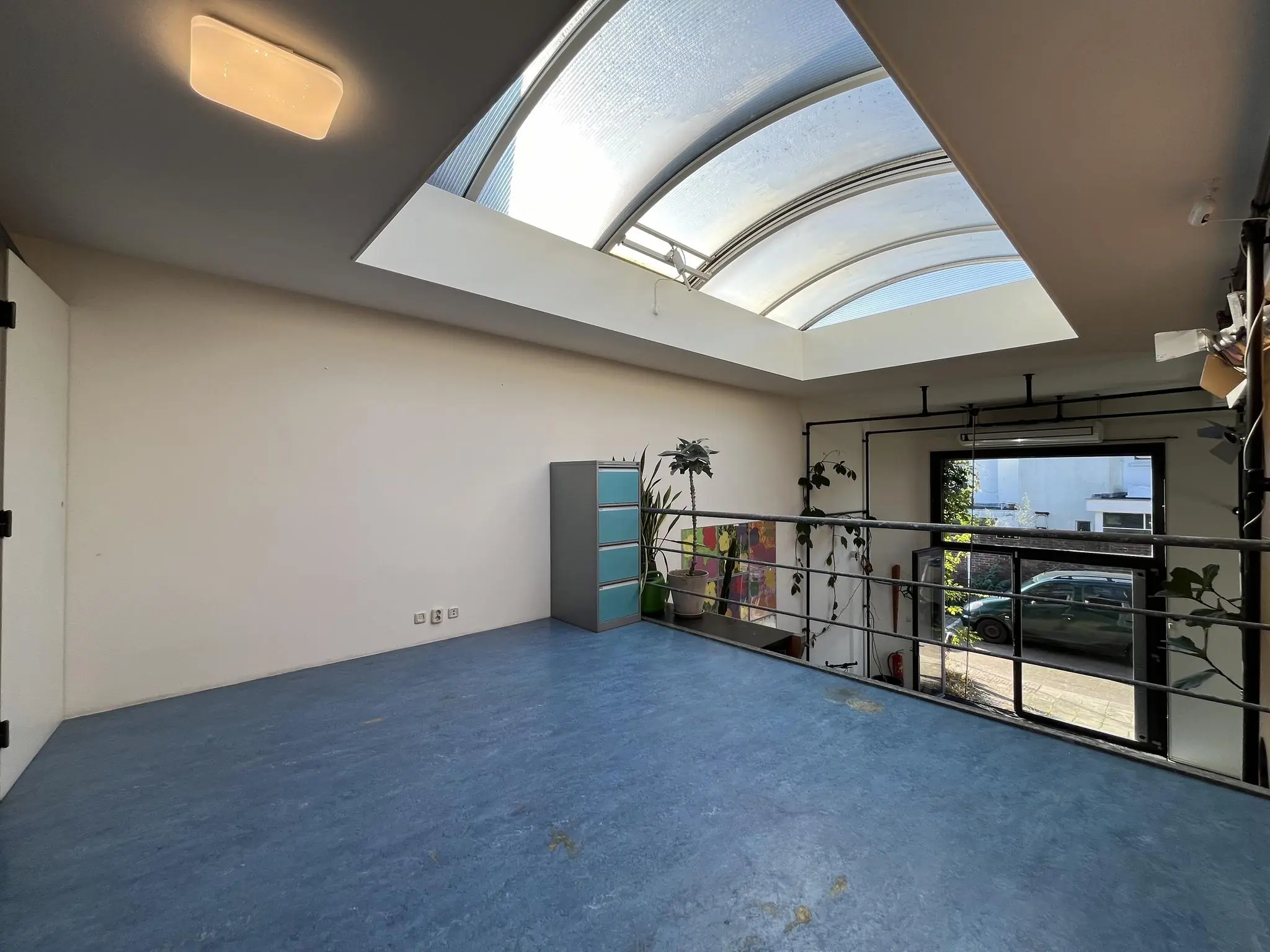 Lichte ruimte op een bovenverdieping aan de Kerkstraat met een blauwe vloer, dakraam en zicht op de straat.