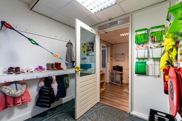 Kinderopvanghal met jassen, schoenen en informatiemateriaal aan de muur bij de Dedemsvaartweg.