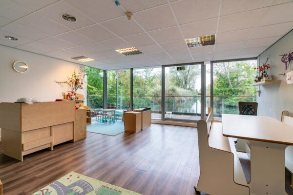 Lichte en ruime kinderdagverblijfruimte aan de Dedemsvaartweg met uitzicht op een vijver en omringd door groen.