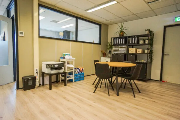 Kantoorruimte aan de Hollantlaan met een ronde vergadertafel, archiefkast en printerhoek.