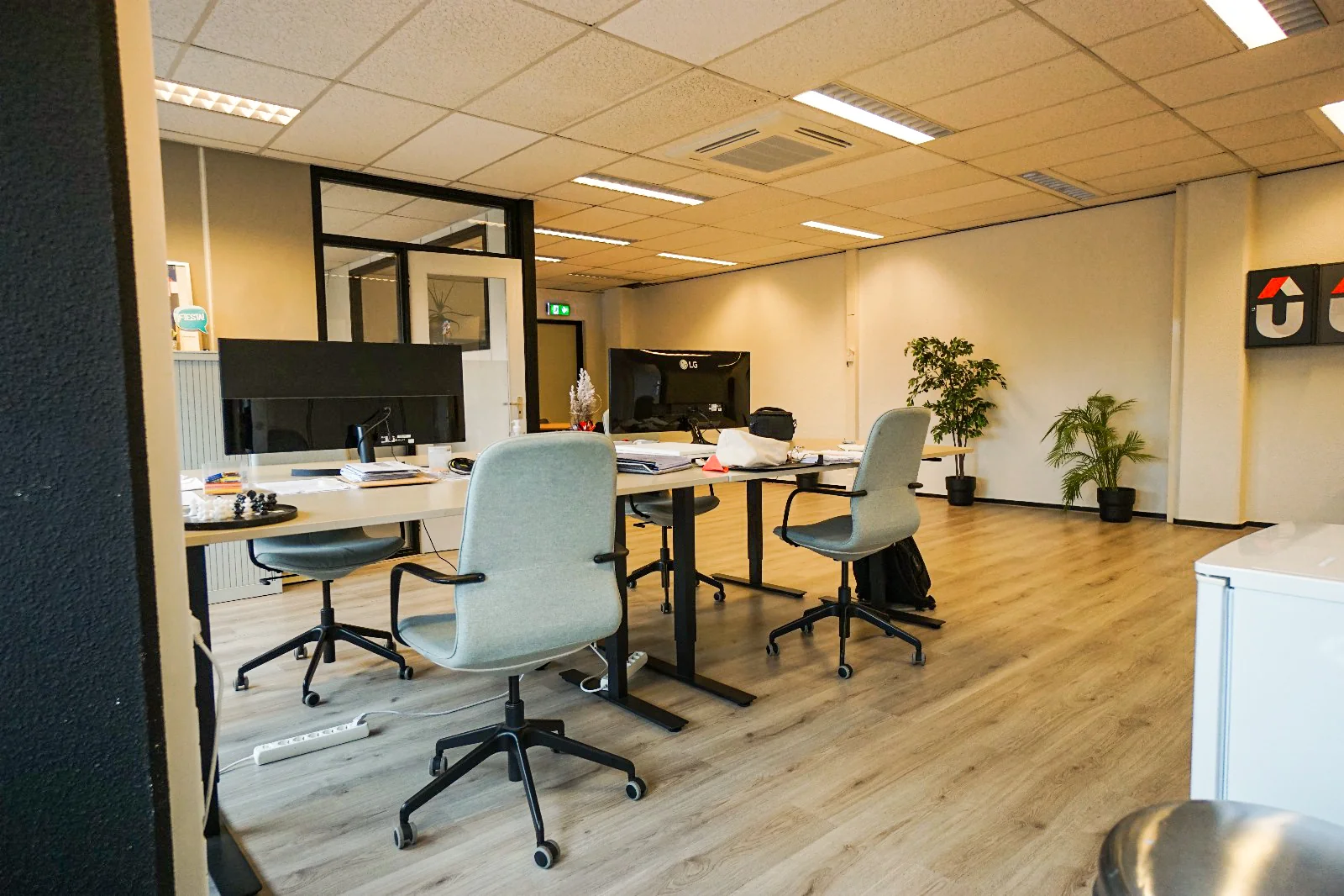 Moderne en netjes ingerichte kantoorruimte aan de Hollantlaan met bureaus, bureaustoelen, planten en computerschermen.