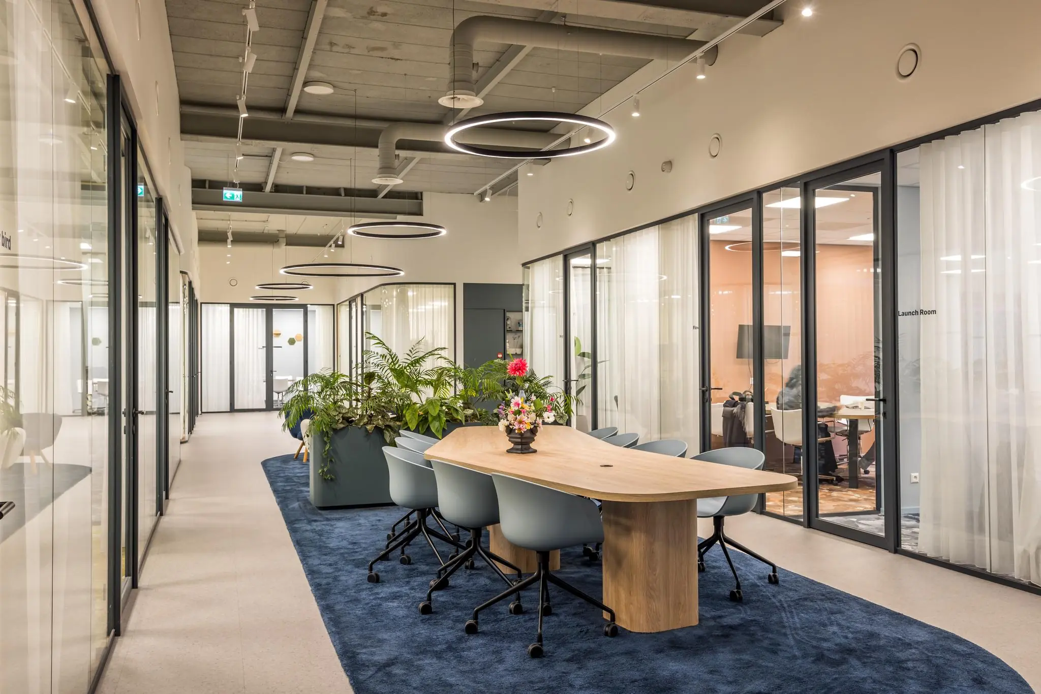 Moderne kantoorruimte aan de Atoomweg met vergadertafel, planten en glazen vergaderruimtes.