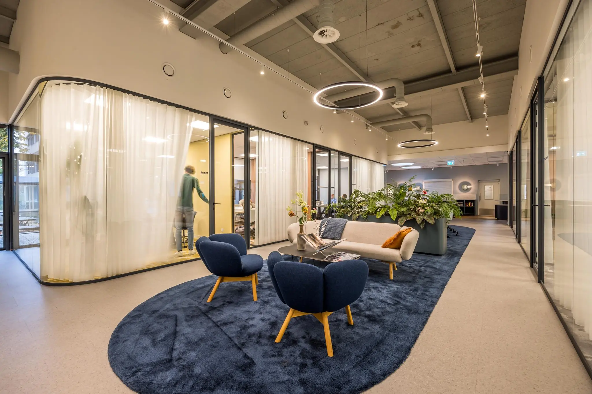 Moderne kantoorruimte aan de Atoomweg met een gezellige loungehoek, glazen vergaderruimtes en sfeervolle verlichting.