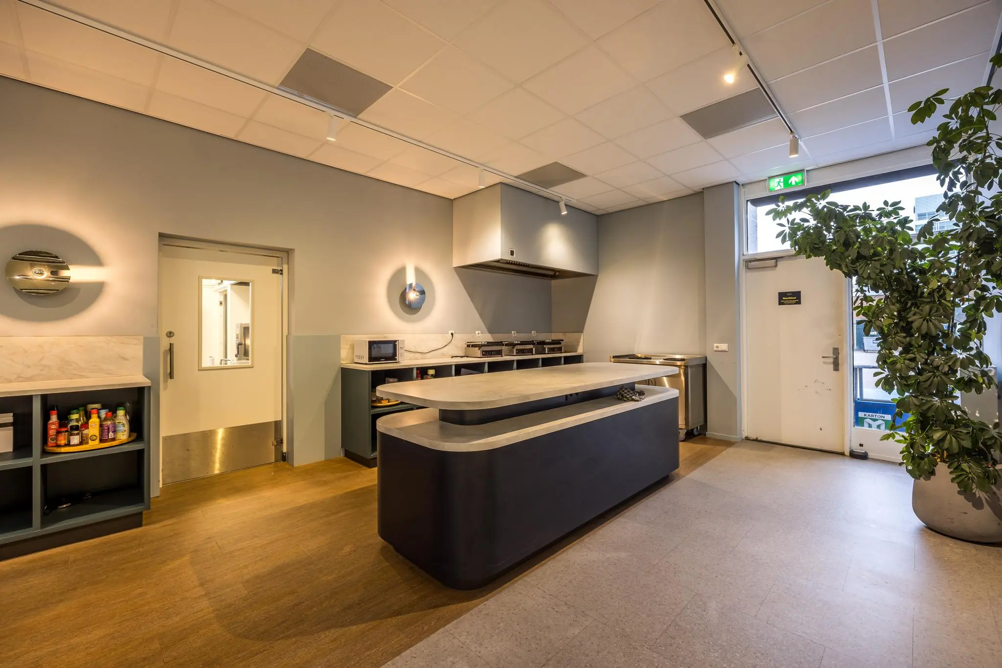 Moderne bedrijfskeuken met kookeiland, wandkasten en apparatuur aan de Atoomweg.