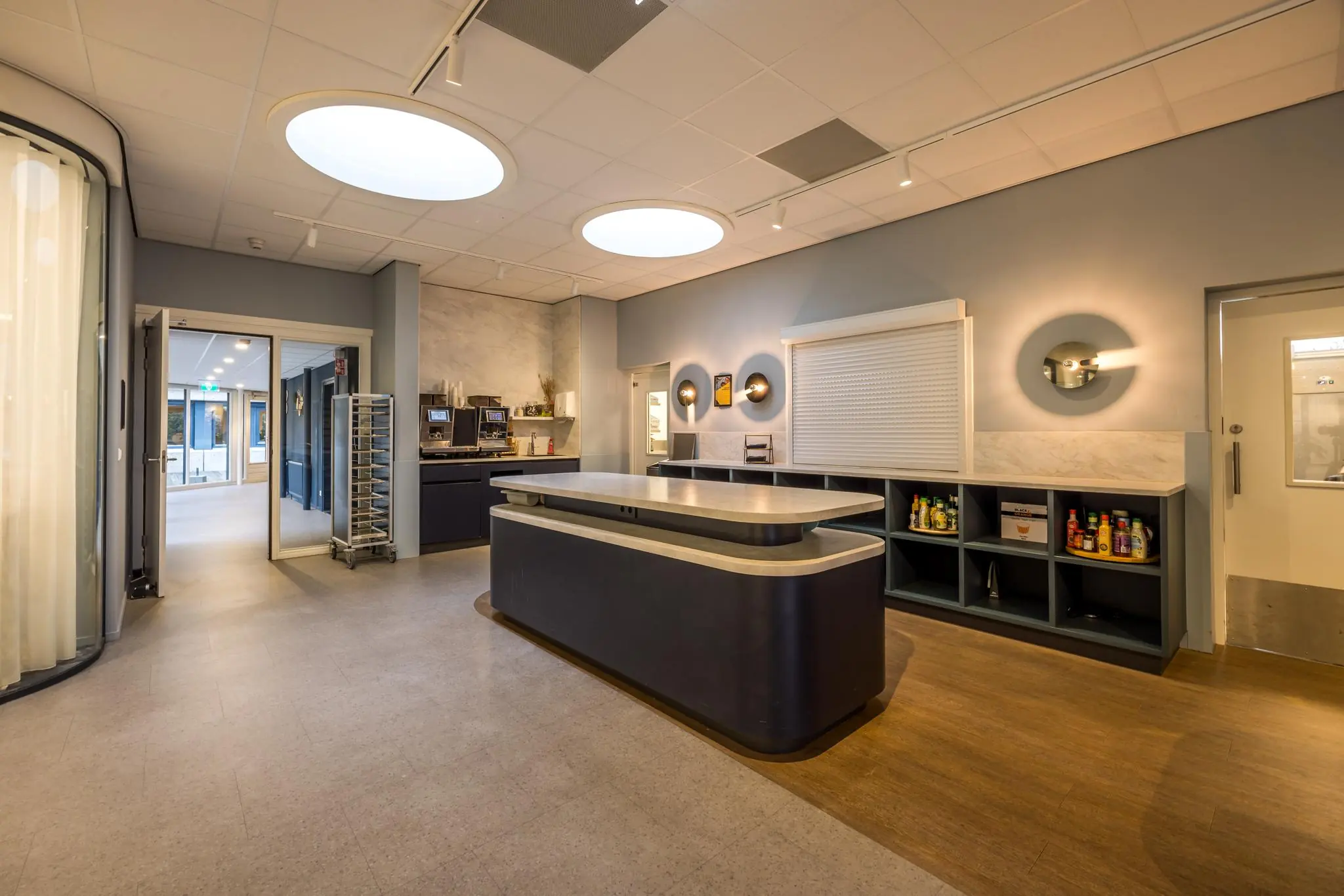 Moderne en strak vormgegeven bedrijfskeuken aan de Atoomweg met groot werkblad, koffieapparaten en open voorraadrekken.