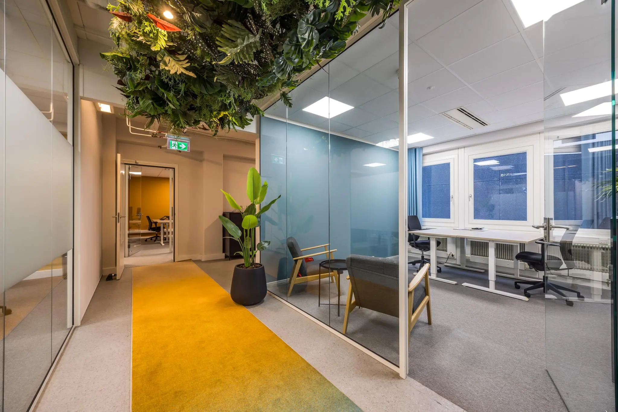 Moderne kantoorruimte aan de Atoomweg met glazen wanden, een gele loper en groene plafonddecoratie.