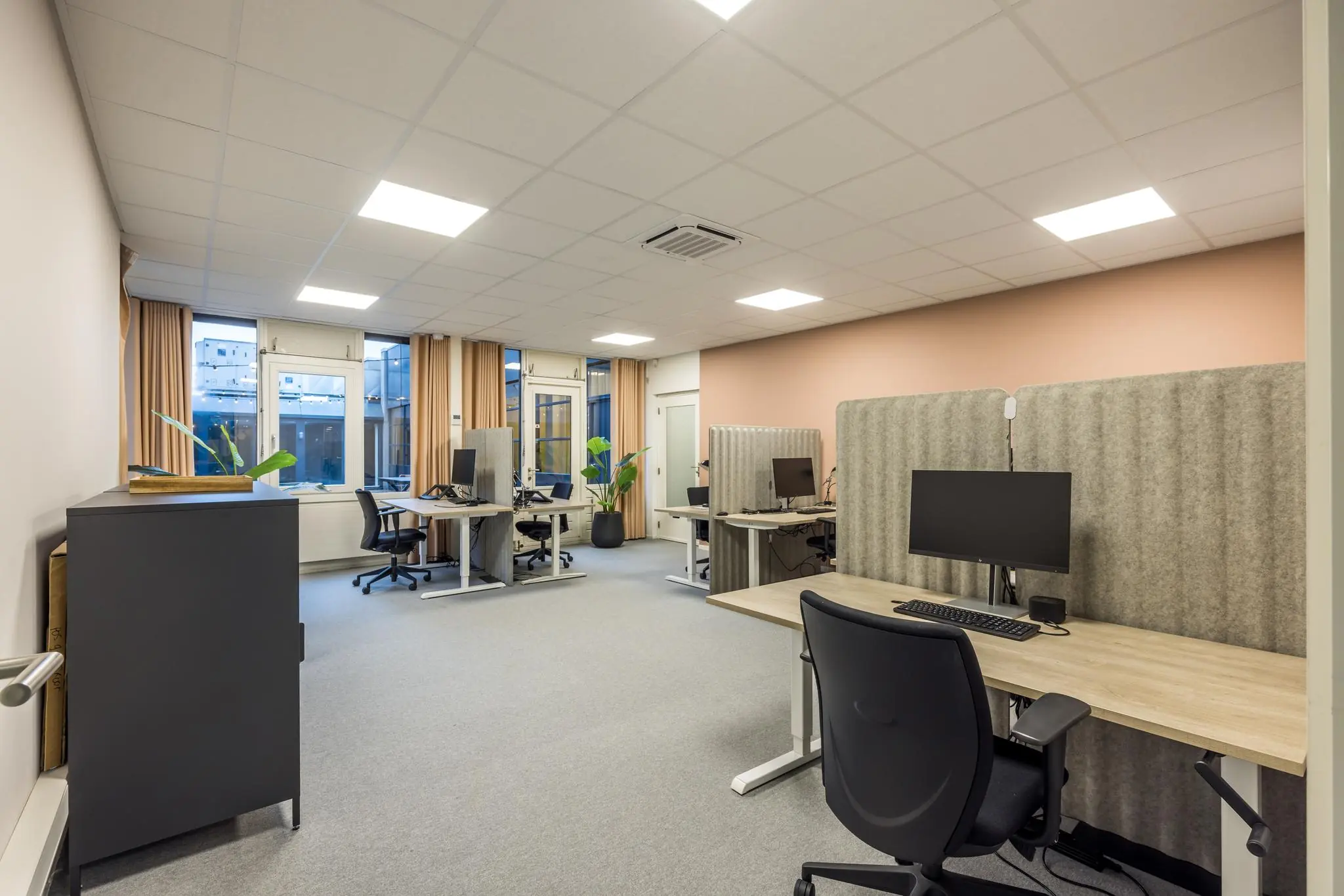 Modern kantoor met meerdere werkplekken, bureaustoelen, computers en geluidsdempende schermen aan de Atoomweg.
