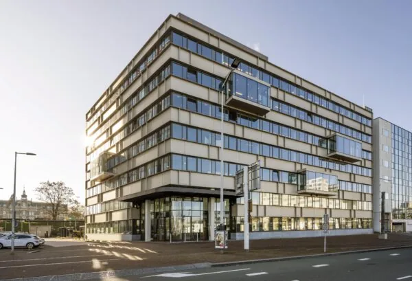 Modern kantoorgebouw aan de De Ruijterkade in Amsterdam met strakke gevel en uitstekende glazen kantoren.