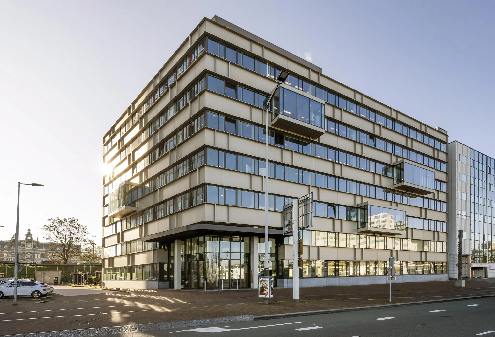 Modern kantoorgebouw aan de De Ruijterkade in Amsterdam met strakke gevel en uitstekende glazen kantoren.