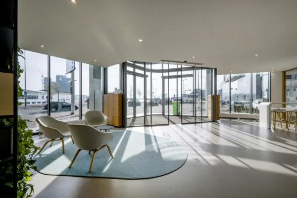 Moderne en lichte ontvangsthal aan de De Ruijterkade met zithoek en glazen draaideur.