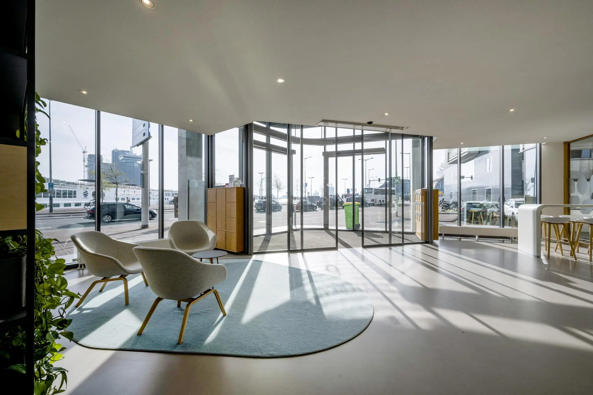 Moderne en lichte ontvangsthal aan de De Ruijterkade met zithoek en glazen draaideur.