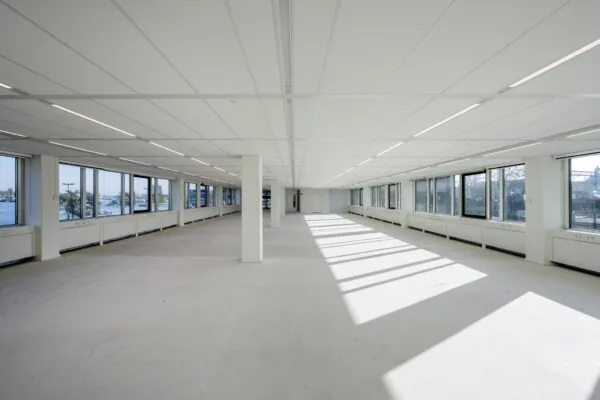 Licht en ruim leeg kantoorinterieur aan de De Ruijterkade met grote ramen en uitzicht op het water.