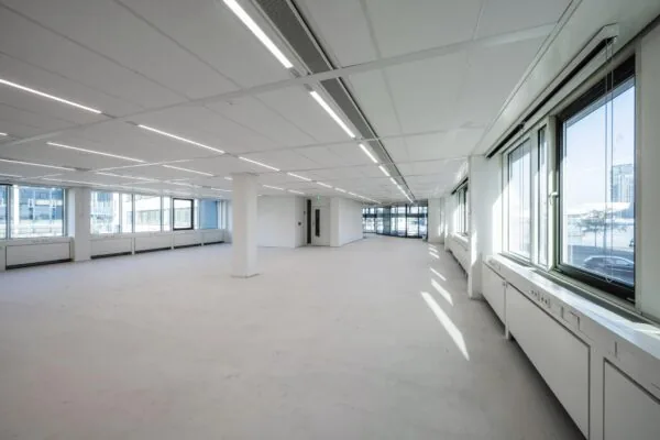 Lichte, lege kantoorruimte aan de De Ruijterkade met grote ramen en systeemplafond.
