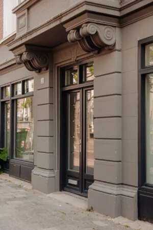 Entree van een klassiek gebouw aan de Plantage Middenlaan met het huisnummer 21 en sierlijke geveldetails.