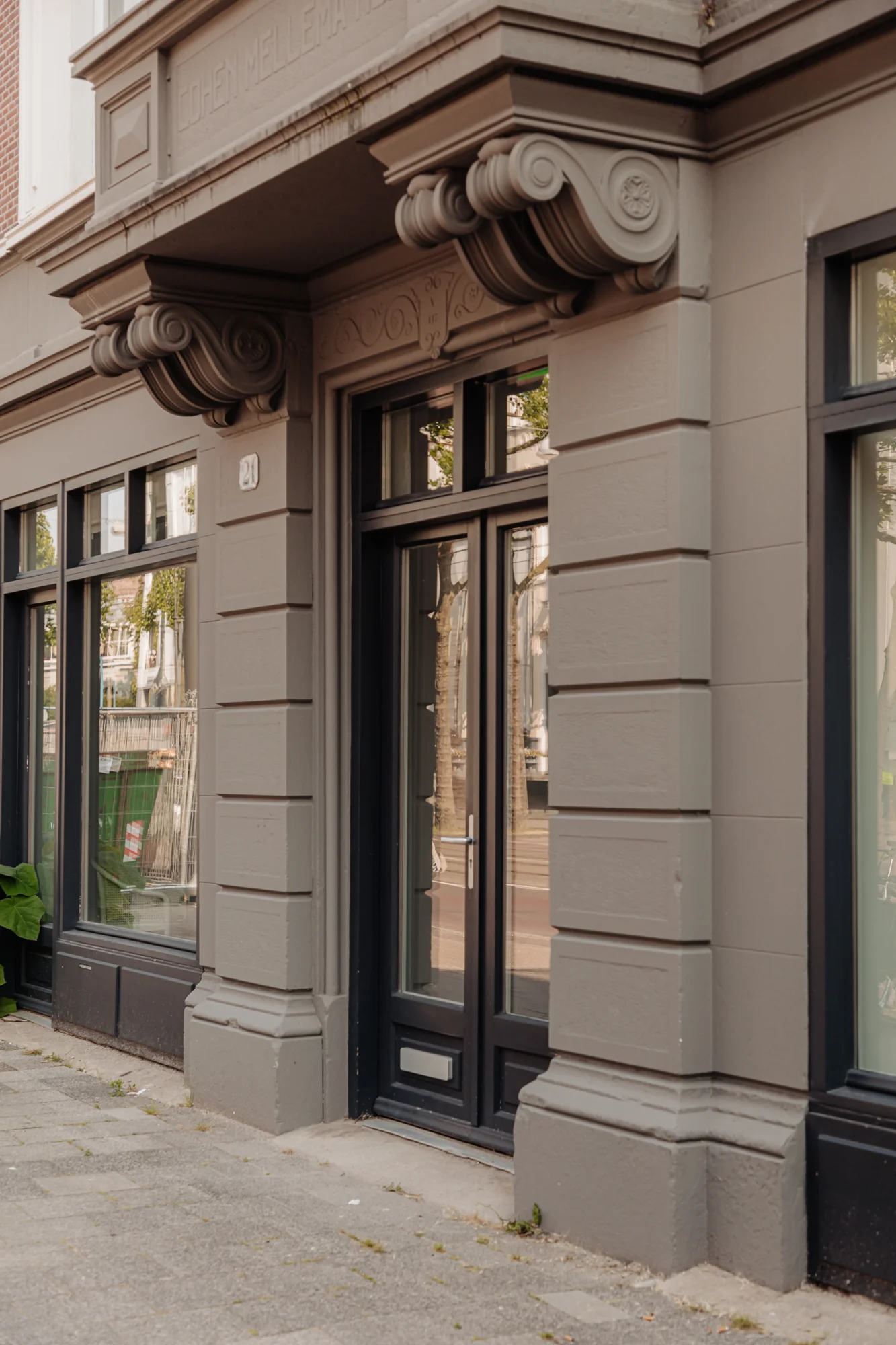 Entree van een klassiek gebouw aan de Plantage Middenlaan met het huisnummer 21 en sierlijke geveldetails.