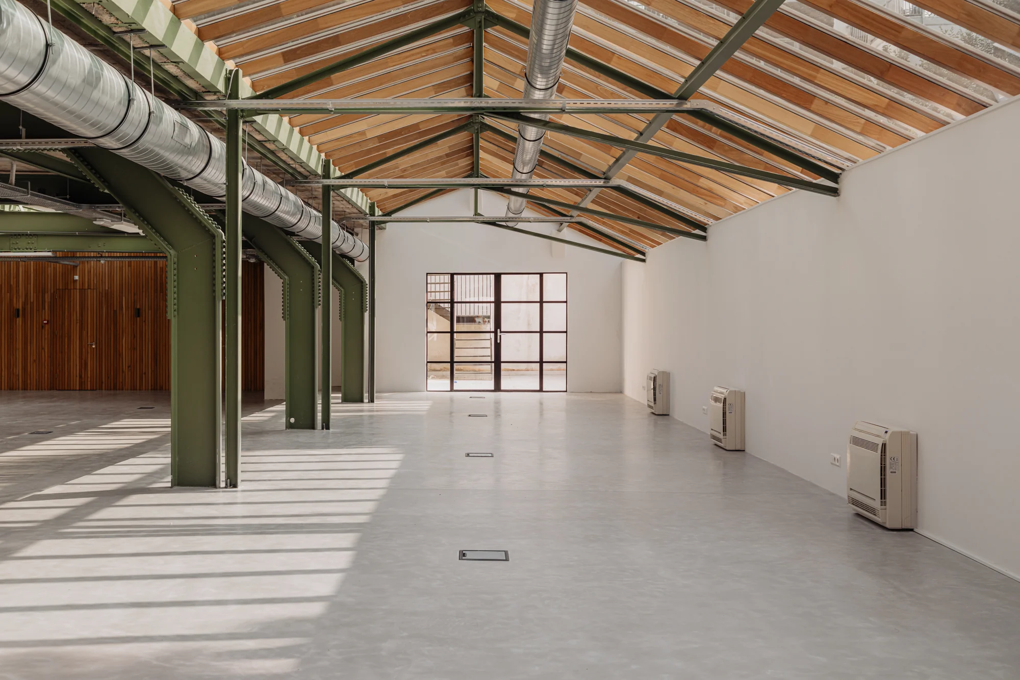 Licht en ruim industrieel interieur aan de Plantage Middenlaan met zichtbare stalen constructie en glazen dak.