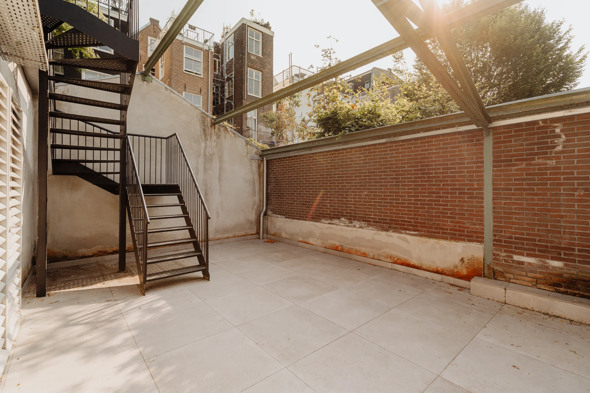 Binnenplaats met een stalen trap en bakstenen muur aan de Plantage Middenlaan in Amsterdam.