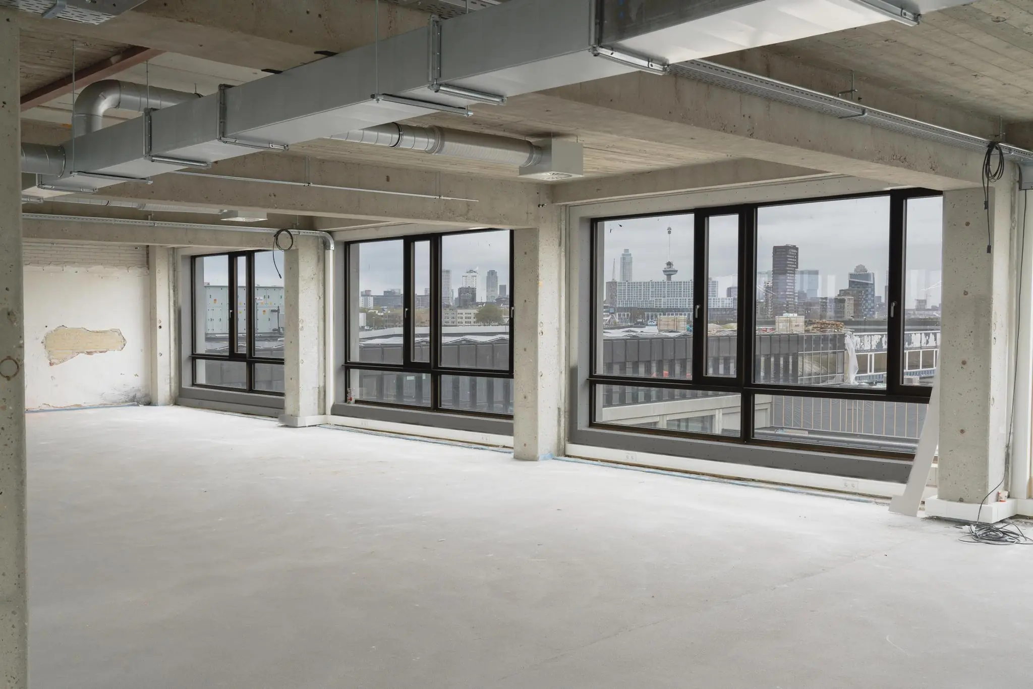 Leeg industrieel kantoorpand aan de Sluisjesdijk met uitzicht op de skyline van Rotterdam.