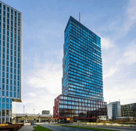 Hoog modern kantoorgebouw aan de P.J. Oudweg in Almere met een glazen gevel en roodkleurige onderbouw.