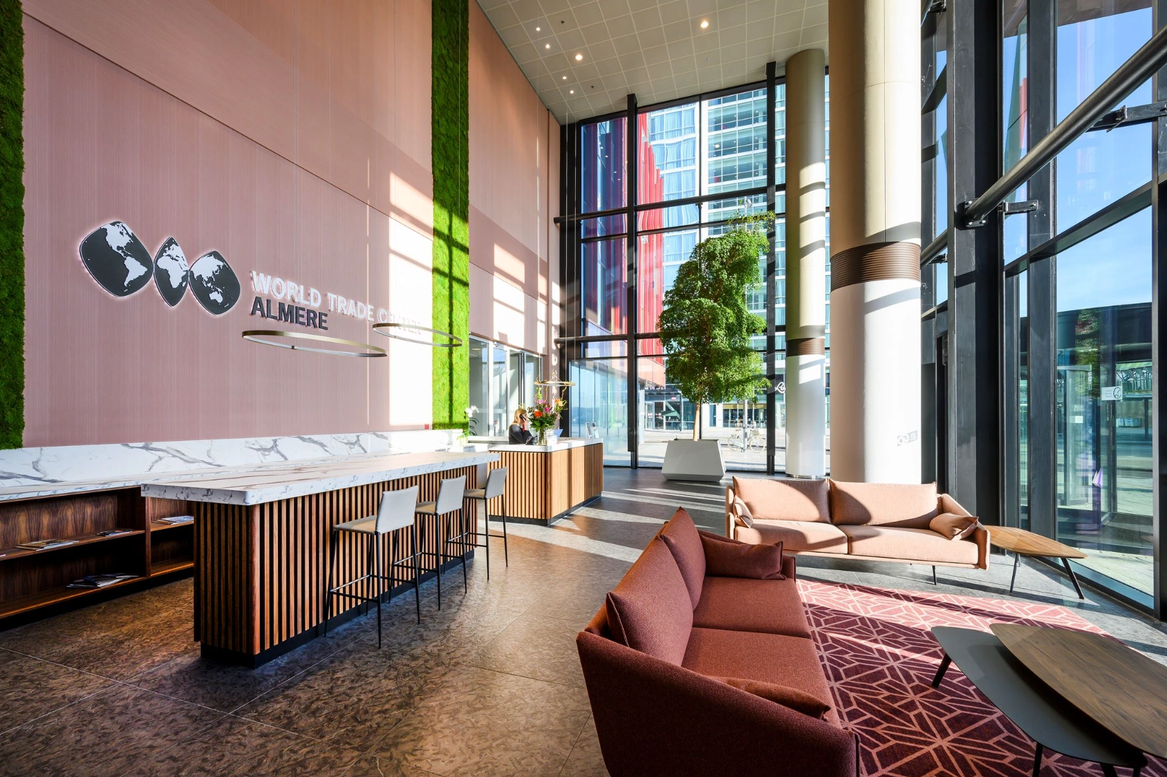 Moderne ontvangsthal van het World Trade Center Almere met zitgedeelte, balie en grote raampartijen.