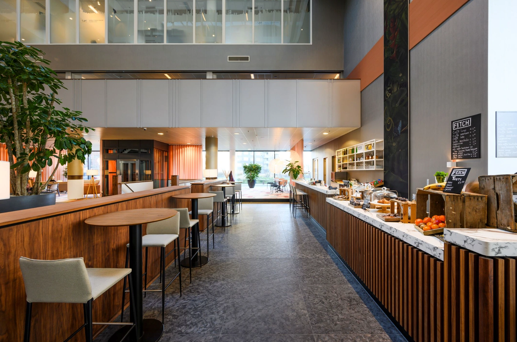 Modern ingerichte koffiebar FETCH aan de P.J. Oudweg met zithoeken, houten accenten en een uitgebreid aanbod aan drankjes en snacks.