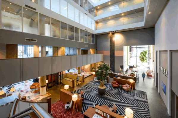 Moderne, open lobby van het World Trade Center aan de P.J. Oudweg met zithoeken, een receptiebalie en meerdere verdiepingen kantoren.