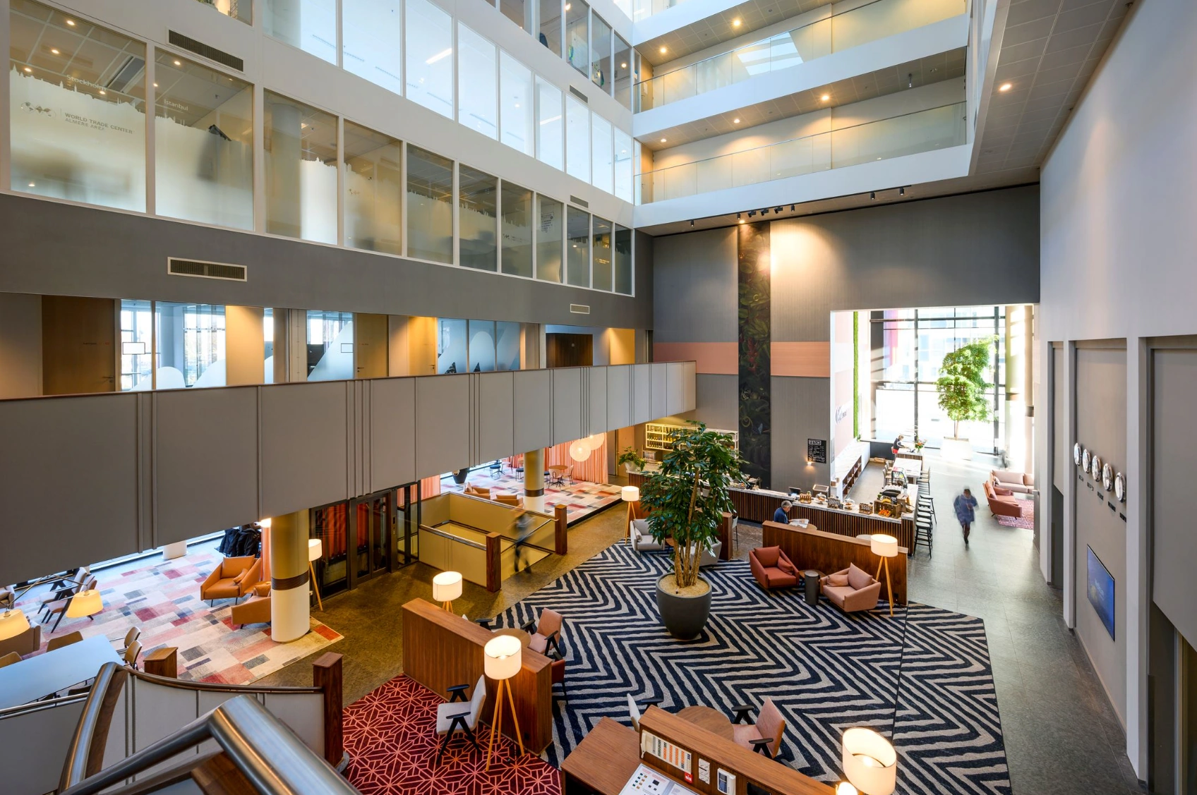 Moderne, open lobby van het World Trade Center aan de P.J. Oudweg met zithoeken, een receptiebalie en meerdere verdiepingen kantoren.