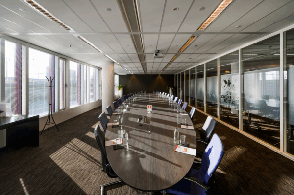 Vergaderruimte met een lange ovale tafel en voorbereidende materialen in het VTC Conference Center aan de P.J. Oudweg.