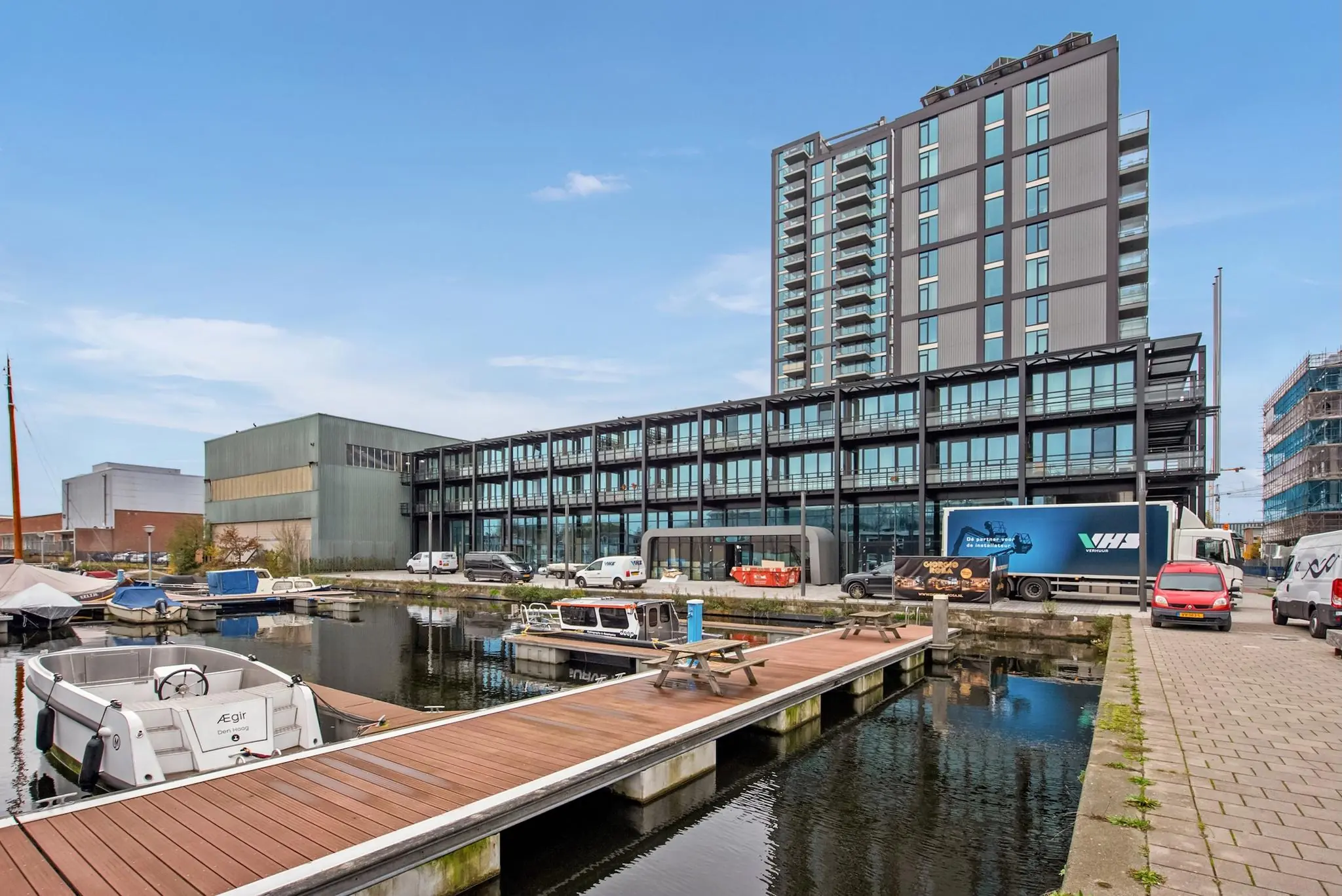 Modern appartementencomplex aan de Saturnusstraat met uitzicht op een jachthaven en aanlegsteiger.