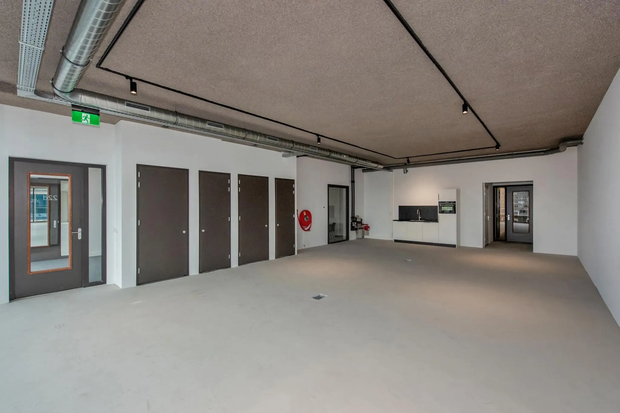 Leeg industrieel kantoorpand aan de Saturnusstraat met meerdere deuren, een pantry en zichtbare ventilatiebuizen aan het plafond.